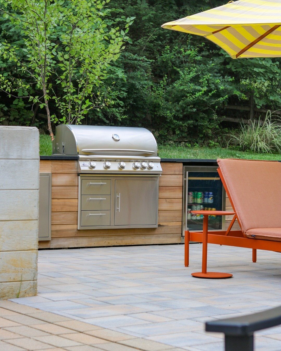 Stainless steel outdoor grill and a built-in beverage fridge set into a wooden kitchen island.