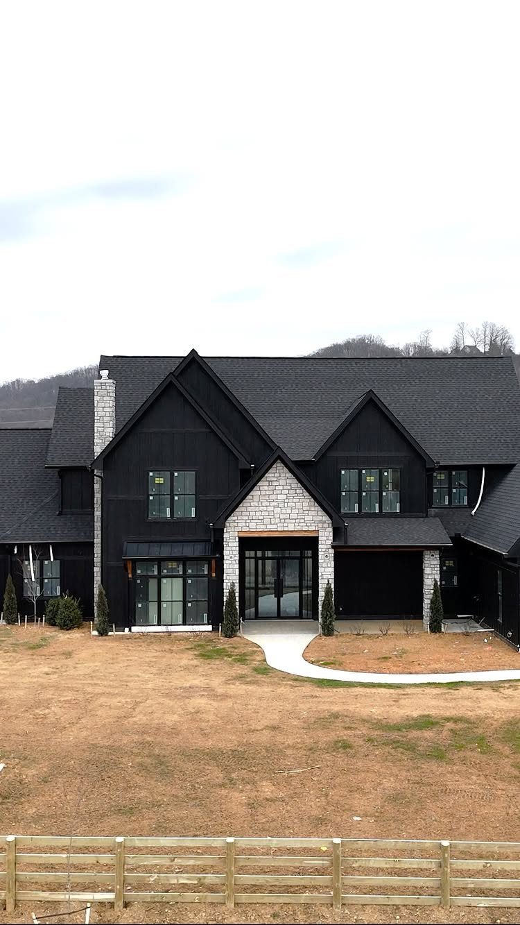 Modern house with black board and batten siding and light gray stone accents.