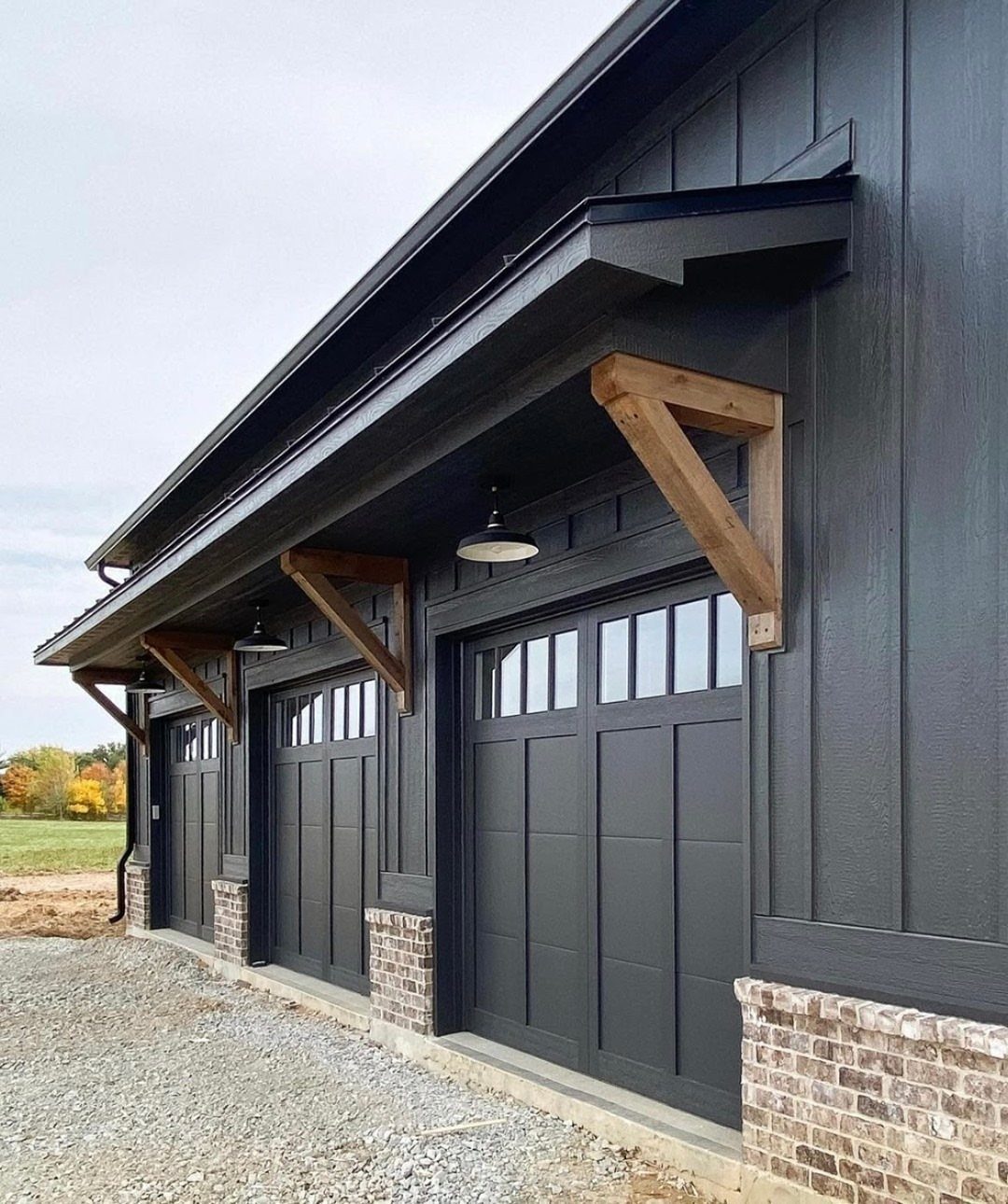 Black board and batten garage exterior with natural wood decorative brackets and black garage doors.