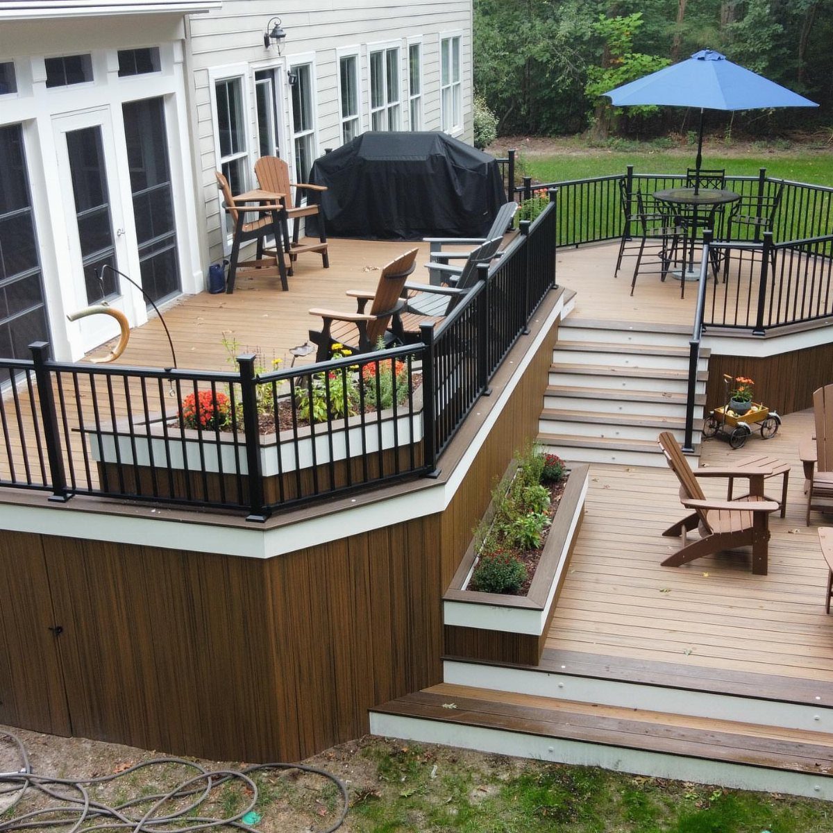Wooden multi-level deck featuring integrated built-in planter boxes with small green plants and flowers.