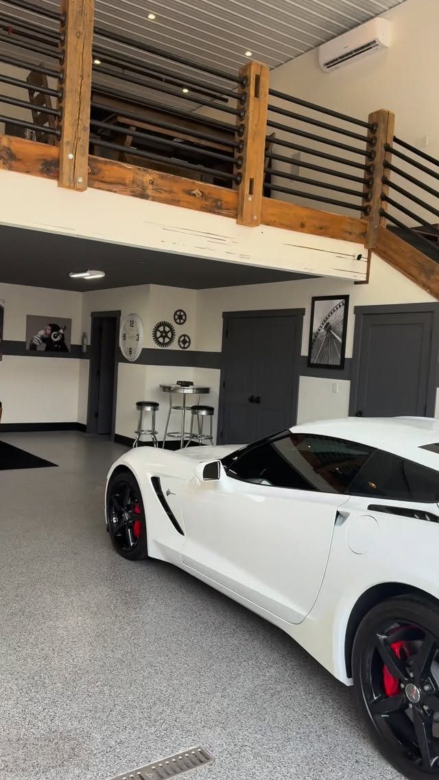 A white sports car parked in a modern, clean garage with a mezzanine level.