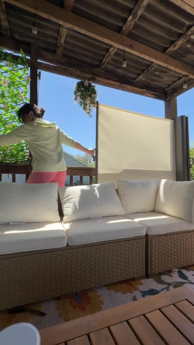 A person adjusting a large light-colored privacy screen on a wooden outdoor deck.