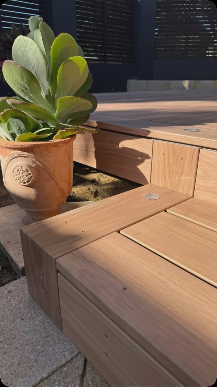 Wooden deck steps made of light timber planks next to a terracotta succulent pot.
