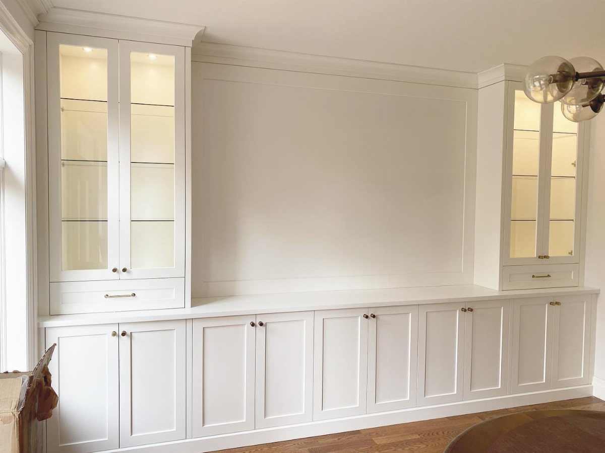 White built-in sideboard with closed lower cabinetry and glass-door upper storage cabinets.