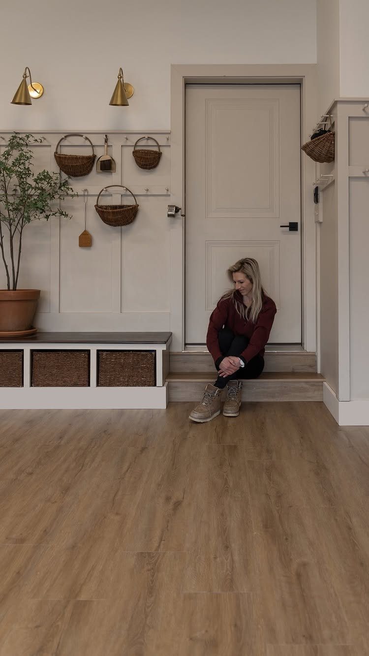 Light wood-look flooring in a mudroom with a white door and built-in bench storage.
