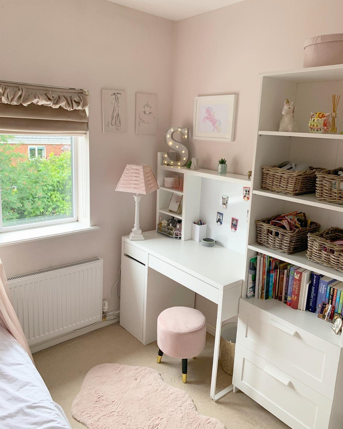 White shelving unit with woven baskets and books in a pink bedroom