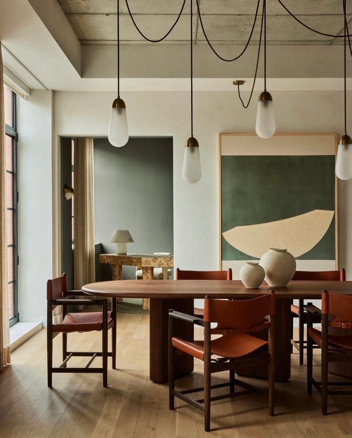 Modern dining room with oval wooden table, leather chairs, and abstract wall art.