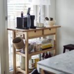 Wooden kitchen storage trolley with coffee station and organized lower shelves.