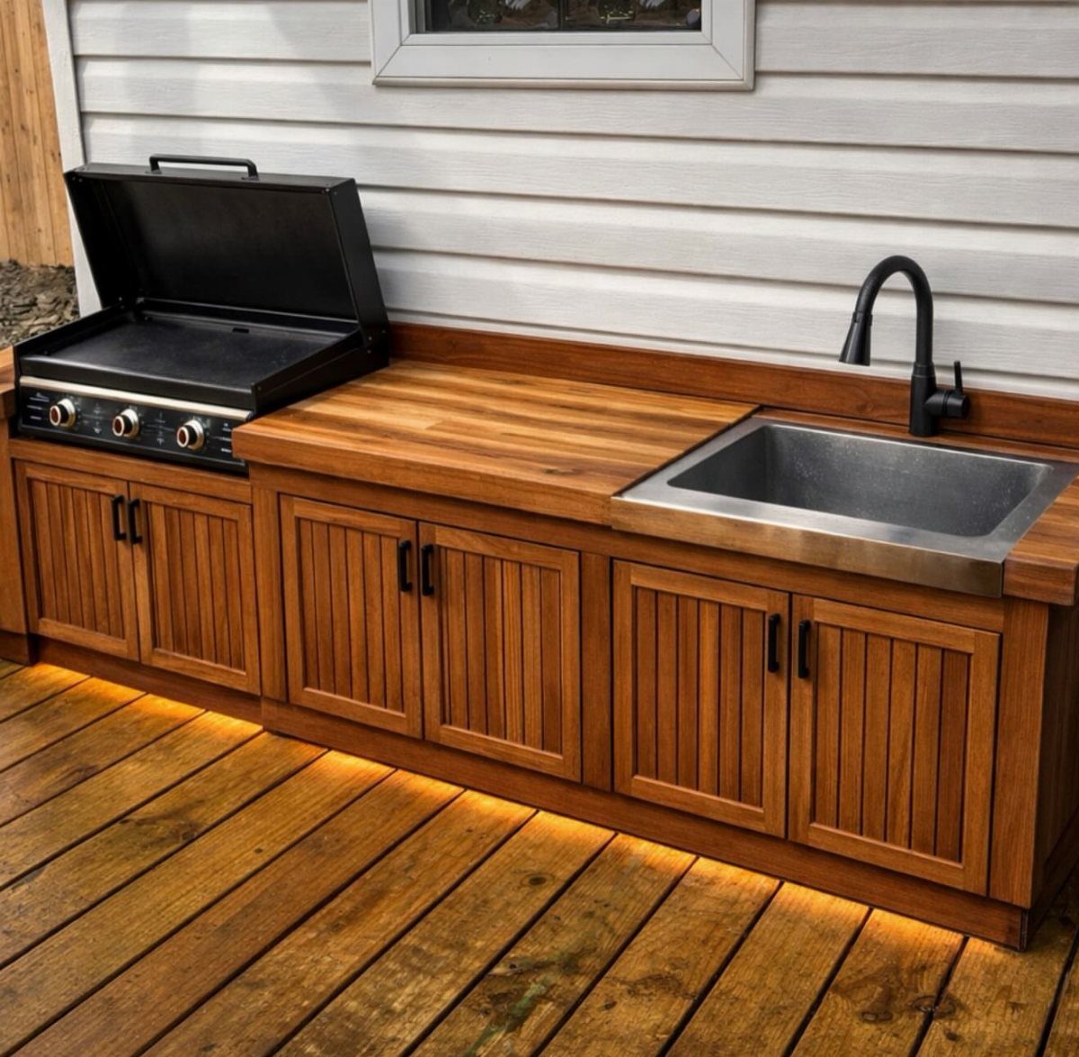 Light wood cabinetry with a built-in griddle and stainless steel sink on a wooden deck.