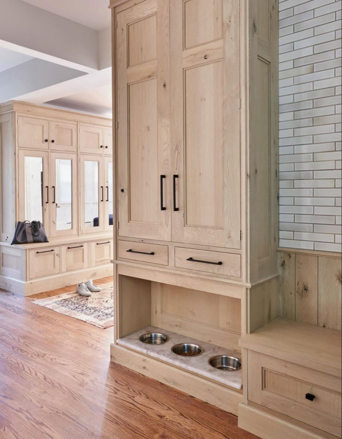 Built-in light wood cabinetry featuring three stainless steel pet bowls at the base.