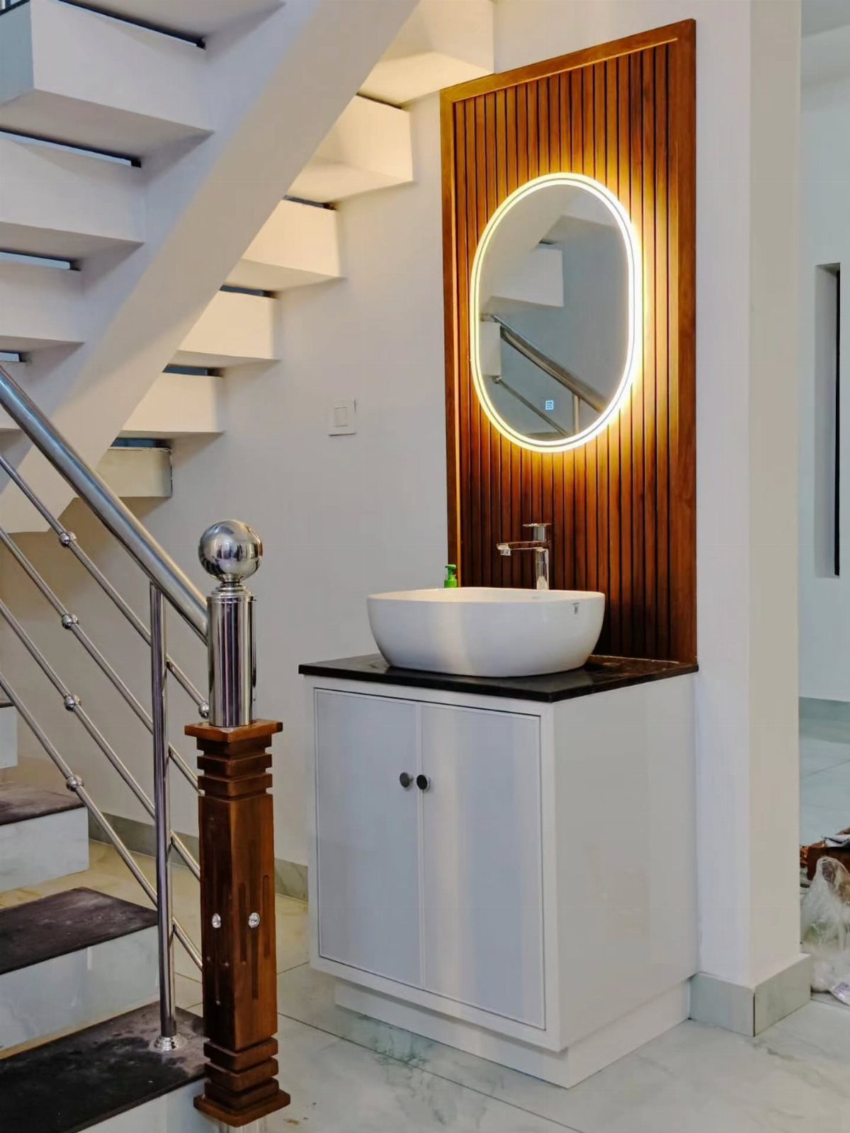 Modern white vessel sink with backlit oval mirror on a wooden slat wall.