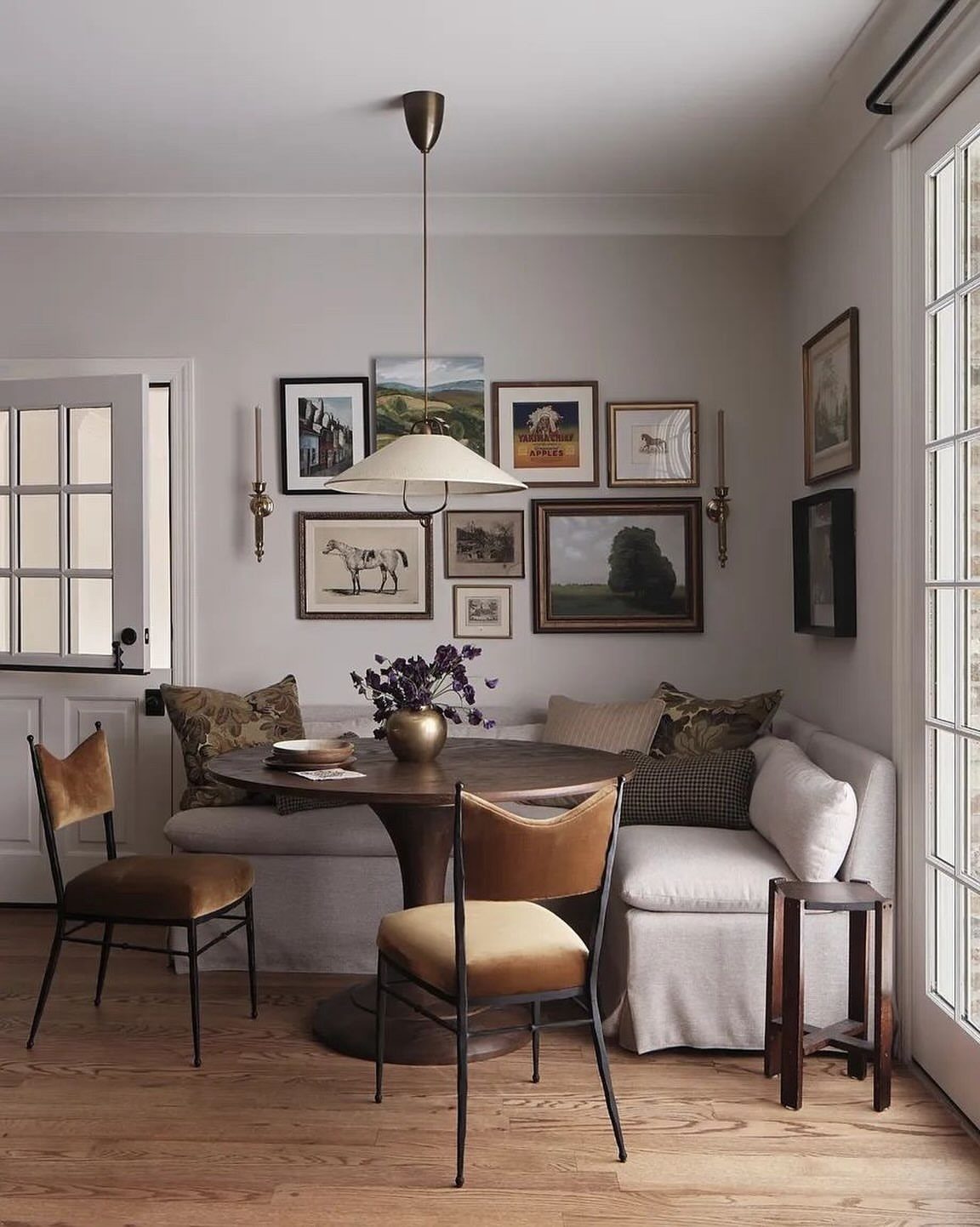 Tan velvet dining chairs with black frames around a round wooden dining table.